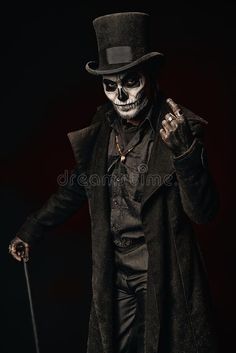 a skeleton dressed in a top hat and coat holding a cane with both hands royalty images