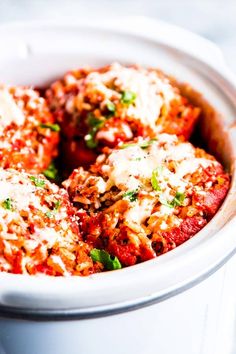 a white bowl filled with meatballs covered in sauce and parmesan sprinkles