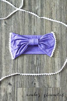 a purple bow tie laying on top of a wooden floor next to a white string