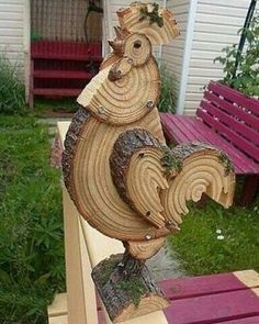 a wooden rooster statue sitting on top of a bench next to a red and purple bench