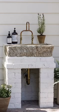 a white brick sink sitting on top of a counter next to potted plants