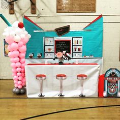 a table with balloons and stools in front of a basketball hoop on the floor