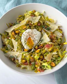 a white bowl filled with shaved brussels sprouts and an egg sitting on top