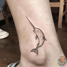 a small dolphin tattoo on the ankle, with an arrow in it's mouth