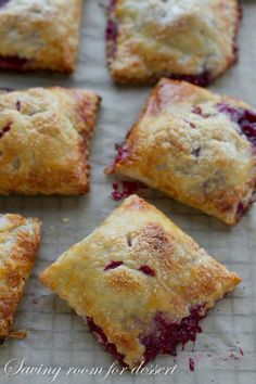 several small pastries on a baking sheet with cranberry sauce and powdered sugar