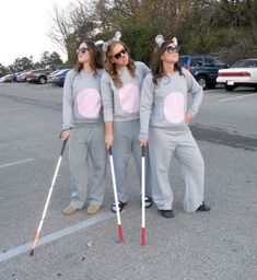 three women in matching outfits are holding crutches and wearing bunny ears on their heads