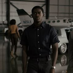 two men are standing in front of an airplane and another man is walking away from the plane