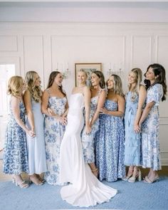 a group of women in dresses standing next to each other on a blue carpeted floor