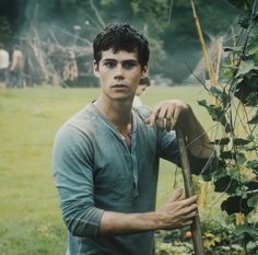 a young man holding a stick in the grass