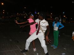 two men are dancing on the street at night