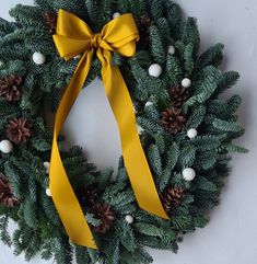 a christmas wreath with pine cones and yellow ribbon