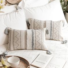 pillows and books on a white bed with flowers in vases next to the pillow