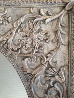 an ornate mirror frame with flowers and leaves on it