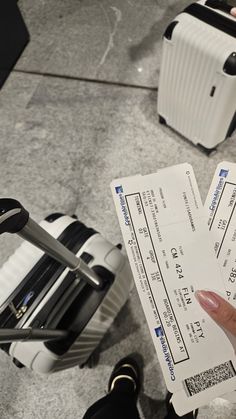 a person holding two checks in their hand while standing next to suitcases and luggage