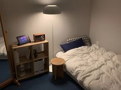 a small bedroom with a bed, night stand and lamp on the side table in front of it