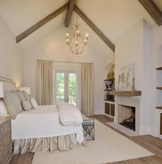 a bedroom with a bed, fireplace and chandelier