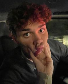 a man with red hair making a funny face in the back seat of a car