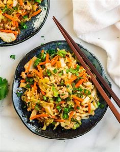 two black plates with stir fry vegetables and chopsticks next to each other on a white surface