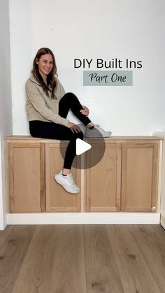 a woman sitting on top of a wooden cabinet in front of a wall with the words diy built ins part one