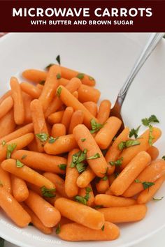 a white bowl filled with carrots and parsley on top of a wooden table