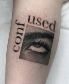 a close up of a person's leg with an eye and words tattooed on it