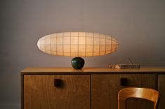 a table lamp sitting on top of a wooden cabinet next to a chair and sideboard