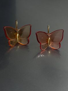 Elevate your style with these stunning Baccarat earrings. Crafted with yellow gold and amber tone crystal/glass, these earrings feature a beautiful butterfly design with a hook closure for easy wear. The dangle/drop style adds a touch of elegance to any outfit and the 1" length is perfect for the lobe area. These earrings are signed by Baccarat and boast a unique combination of beauty, nature, art, animals & insects, bohemian, and fashion & costumes themes. The crystal/glass material adds a spar Gold Earrings With Butterfly Charm For Formal Events, Gold Earrings With Butterfly Charm For Formal Occasion, Luxury Clear Earrings For Formal Events, Luxury Amber Drop Earrings, Elegant Butterfly Earrings For Formal Occasions, Orange Clip-on Earrings For Formal Occasions, Formal Orange Clip-on Earrings, Gold Butterfly Earrings For Formal Occasions, Luxury Yellow Gold Butterfly Earrings