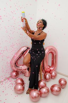 a woman sitting on top of a chair in front of balloons and confetti