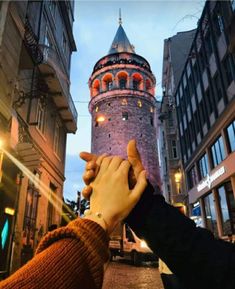 two people reaching out their hands to touch each other in front of an old building