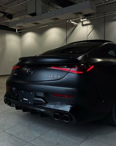 the rear end of a black car parked in a garage