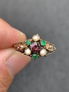 Delicate and Unique Victorian ring  Circa 1857 Many hallmarks - including 375 beautiful goldwork...a lost art! Hallmarked Birmingham 1857  3 Green Emeralds with surface wear  measuring approx. 2.25mm round faceted...sold to me as genuine but I think they may be paste (glass) which was customary in this era 3 pearls 3mm Genuine 4mm cushion cut garnet with surface crack...see photos 1 gram weight Natural patina ( antiquing) which could be cleaned but I leave the pieces as I find them unless they a Victorian Gold Emerald Ring, Victorian Emerald Ring In Yellow Gold, Antique Gold Multi-stone Emerald Ring, Victorian Yellow Gold Emerald Ring, Antique Gold Emerald Ring With Multi-stone, Victorian Style Collectible Emerald Ring, Antique Multi-stone Ruby Ring, Victorian Multi-stone Ruby Ring In Gold, Victorian Gold Ruby Ring With Multi-stone