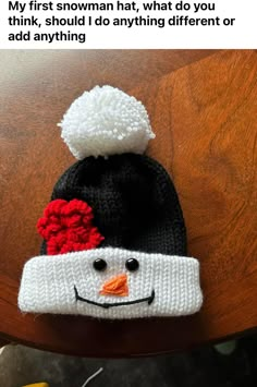 a knitted snowman hat sitting on top of a wooden table