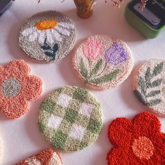 four crocheted flower coasters sitting on top of a table next to a plant