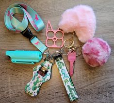 several keychains and other items are laid out on a wooden surface, including a pink pom - pom