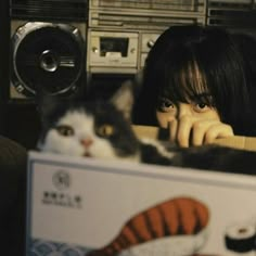 a woman is looking out from behind a box with a cat in front of her