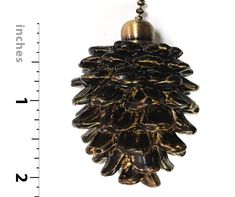 a close up of a pine cone shaped object on a white background with a ruler