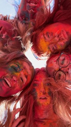 a group of people with their faces painted red and yellow are looking up at the camera