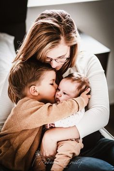 a woman and two children cuddle on the lap of her mother's lap