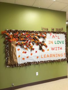 a bulletin board with fall leaves on it in an office hallway, reading fall in love with learning