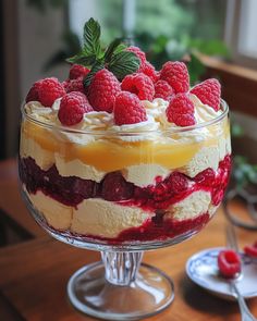 a trifle with raspberries and cream in a glass dish on a table