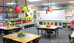 an empty classroom with desks and chairs in front of the windows filled with paper lanterns