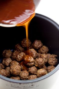 the sauce is being poured on top of meatballs in a bucket with other foods