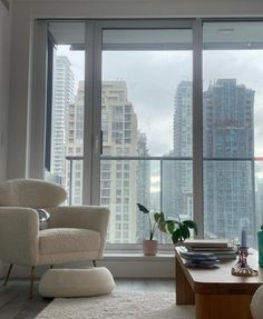 a living room filled with furniture and tall buildings in the background on a cloudy day