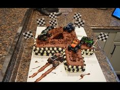 a cake made to look like a race track with monster trucks on it and checkered flags