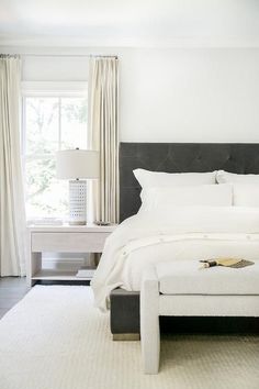 a white bedroom with a large bed and two lamps on either side of the bed