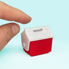 a small red and white object is being held by a person's finger on a blue background