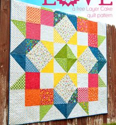 a colorful quilt hanging on the side of a wooden fence with text overlay that says love