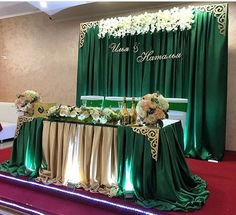 a green and gold wedding setup with flowers on the table