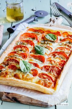 a square pizza with tomatoes and basil on it