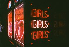 neon signs on the side of a building advertising girls